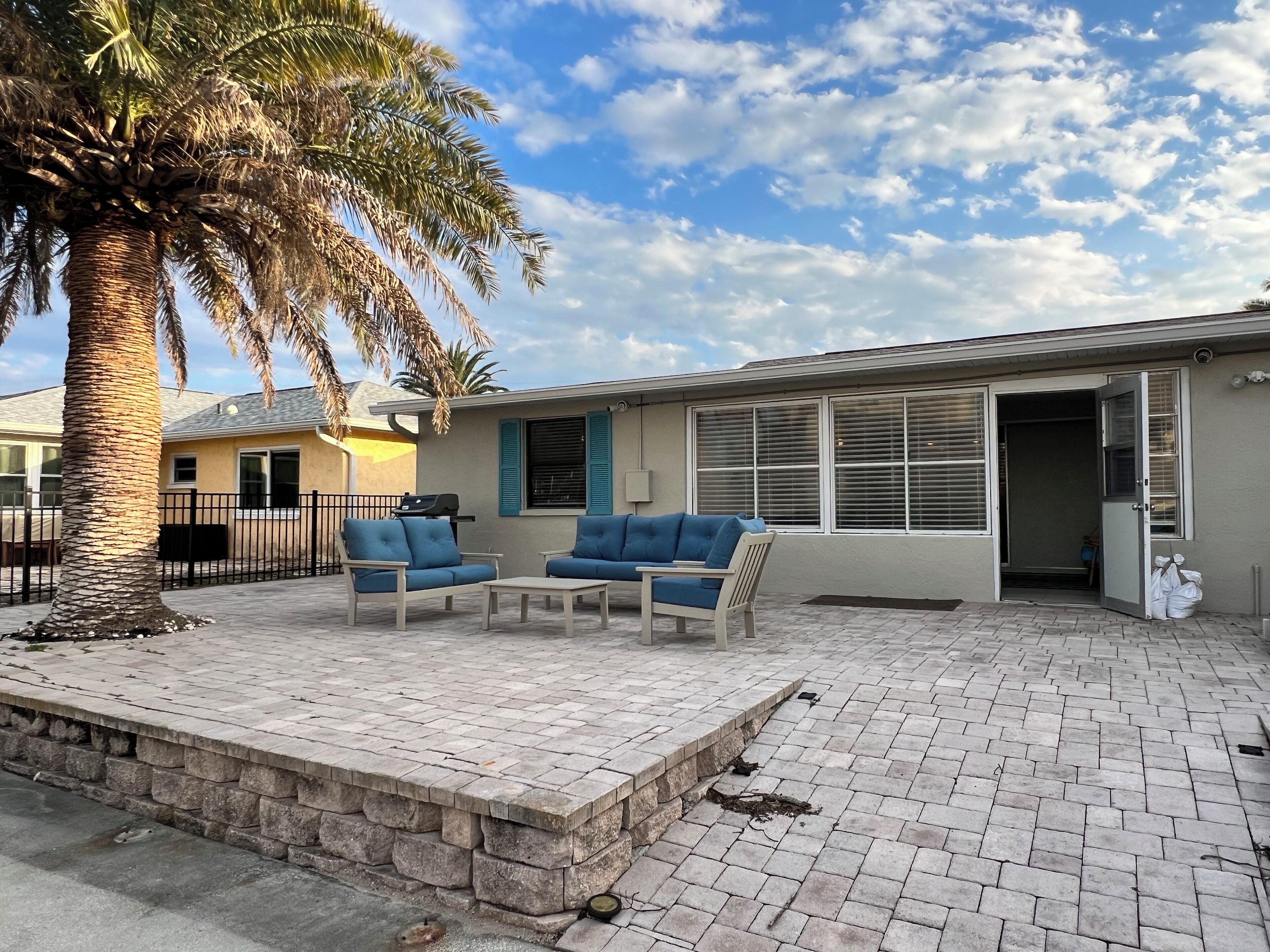 A patio area with two blue cushioned chairs, a small table, and a palm tree.