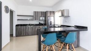 Eine moderne Küche mit einer zentralen Kochinsel, Barhocker und eingebauten Geräten.