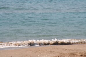 A beach with waves gently lapping at the shore. - R141 - C6 Manila Resort Patio (Calafell)