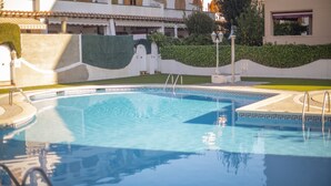 A swimming pool with a geometric tile pattern, surrounded by a low hedge and a white wall with a decorative border. - R141 - C6 Manila Resort Patio (Calafell)