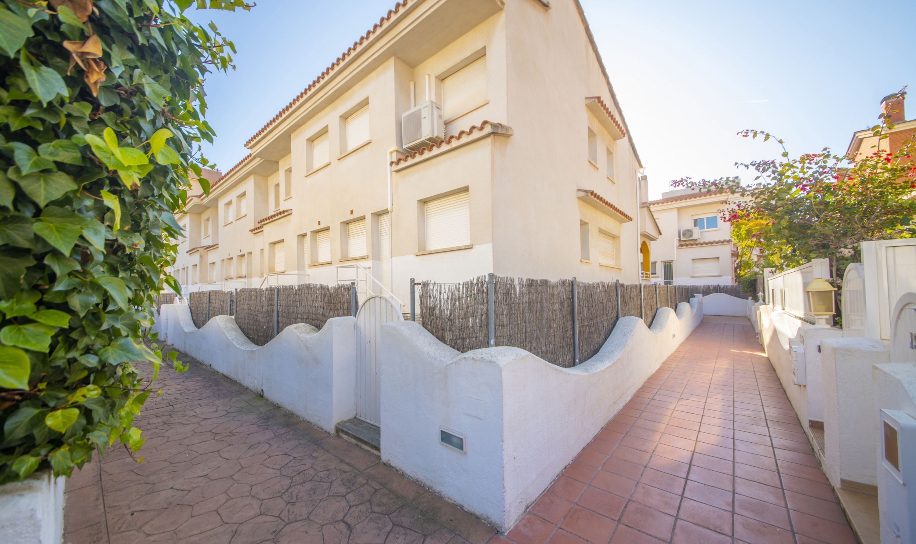 Un edificio con un sendero empedrado y una pared blanca con cerca de madera.
