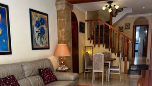 A living room with a sofa, coffee table, and a staircase leading to another level. - Cervantes in Javea X bia (Javea)