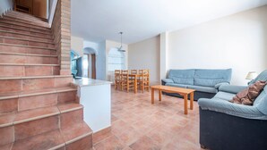 Ein Wohnzimmer mit Treppe, einer Couch, einem Esstisch und Stühlen.