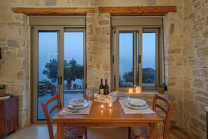 A dining table set for two with wine bottles, candles, and a menu box. - Zen Luxury Villa - South Crete (Faistos)