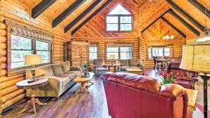 A log cabin interior with a high ceiling, wooden walls, and a cozy seating area with sofas and a red leather chair. - Rustic Pinetop Log Cabin w/ Fire Pit + Grill! (Pinetop)