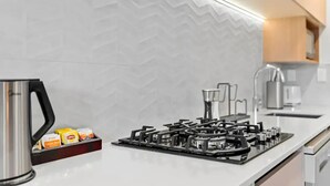 A modern kitchen with a gas stove, a kettle, and a box of tea bags.
