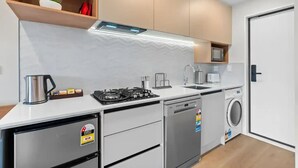 A compact kitchen with a gas stove, dishwasher, microwave, and a small sink.