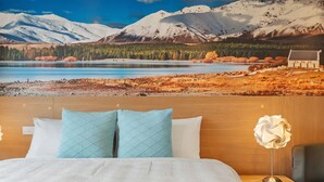 Un dormitorio con cama, dos almohadas, una mesita de noche, una lámpara y vistas a un paisaje montañoso.