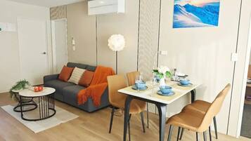 A modern living room with a sofa, coffee table, and dining table set for four.