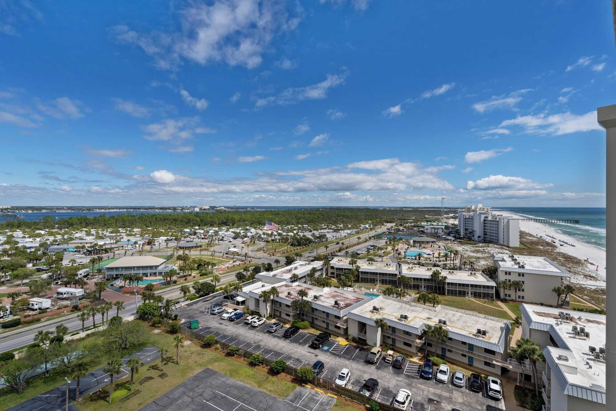 A coastal town with a marina, beachfront, and a hotel with multiple floors and parking.