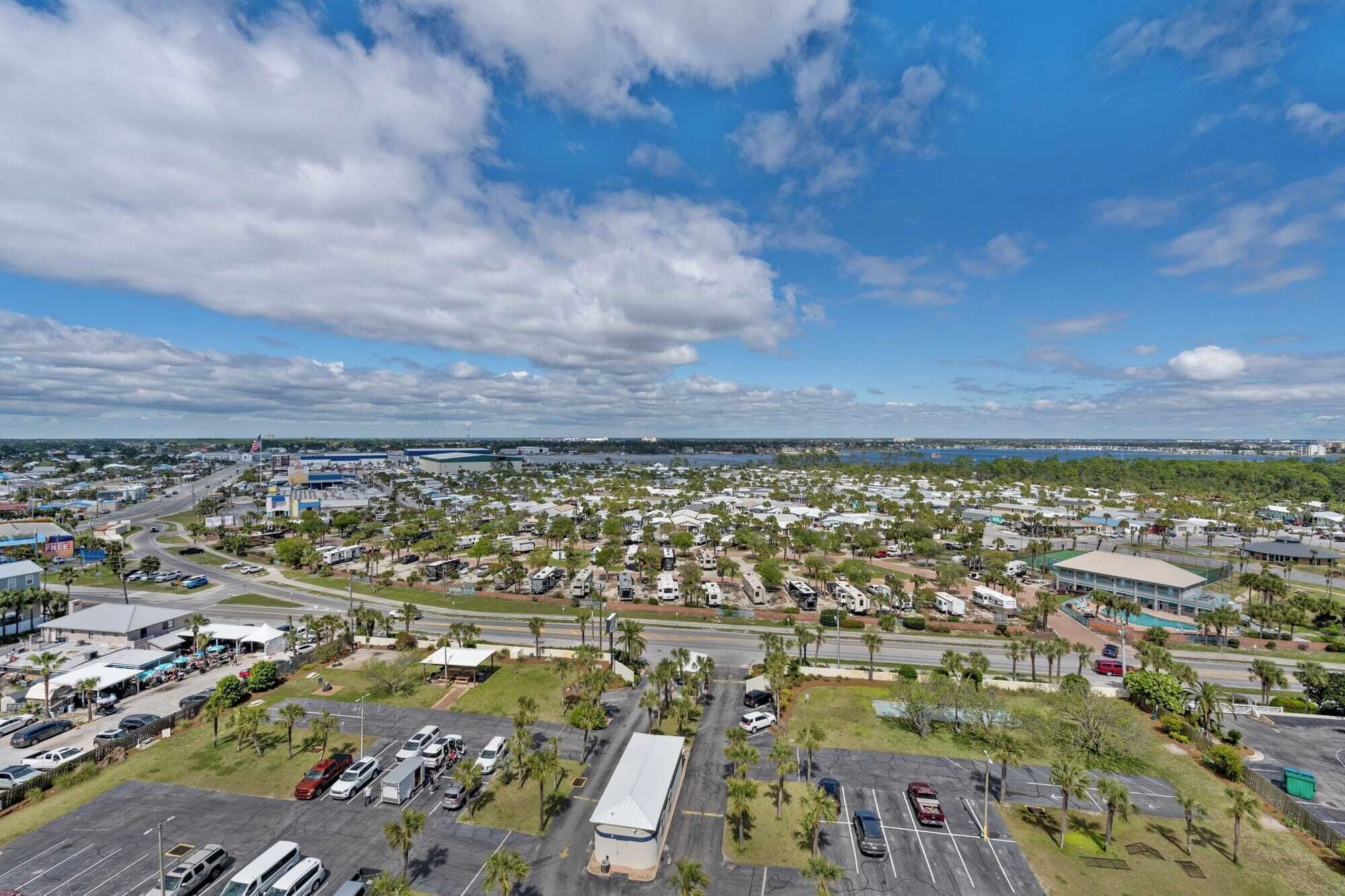 A large RV park with multiple RVs parked in designated areas, surrounded by greenery and a few buildings.