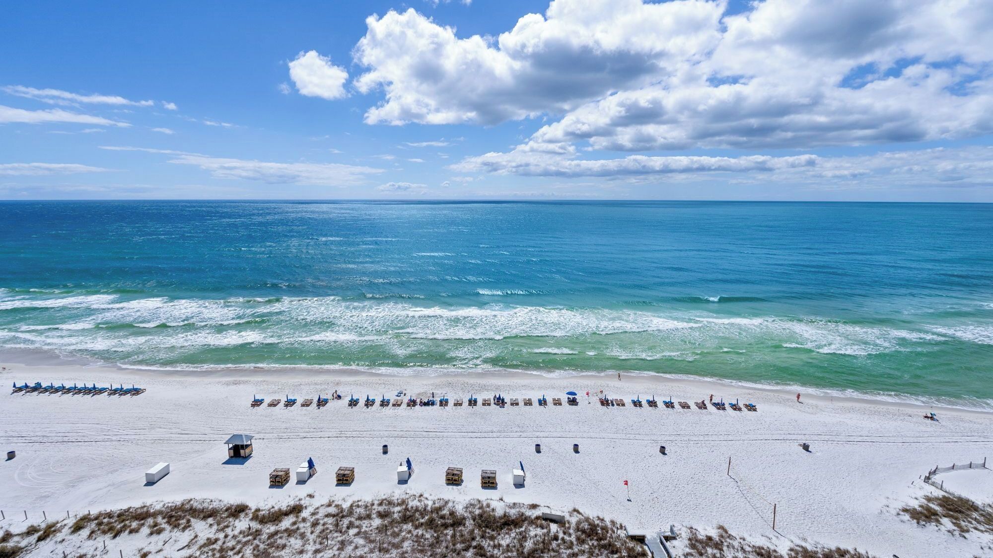 A beach with rows of sun loungers and a lifeguard tower.