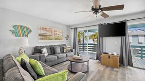 A modern living room with a grey sofa, a round coffee table, and a ceiling fan. - Aqua Horizon by Avantstay Pool, Near the Beach (Panama City Beach)