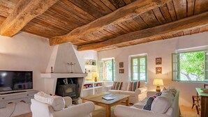 Una sala de estar acogedora con chimenea, muebles blancos y televisor.