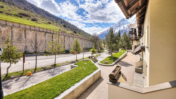 Une vue sur la montagne depuis un balcon, un chemin pavé et un bâtiment à la façade en bois.