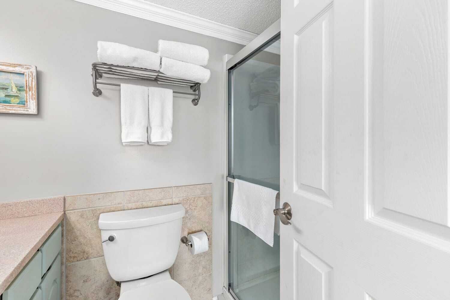 Un baño con inodoro, toallero y puerta de ducha.