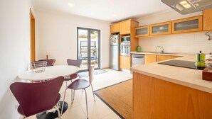 Une cuisine moderne avec des meubles en bois, un réfrigérateur en acier inoxydable, un four et un lave-vaisselle. On y trouve également un coin repas avec une table ronde et des chaises.