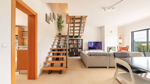 Un salon moderne avec un escalier, un canapé, une table à manger et un téléviseur.