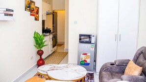 A compact living space with a kitchenette, a dining area with a marble table, and a grey sofa. - Studio Sleeps 2 with 24hr Check-in (Nairobi)