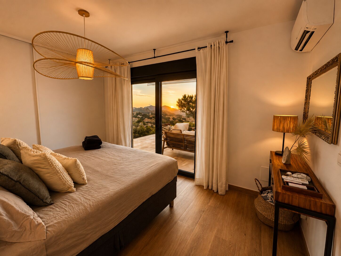 Ein Schlafzimmer mit einem Bett, einem Nachttisch, einer Lampe, einem Spiegel und Blick ins Freie.