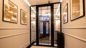 A hallway with framed historical documents, a black-framed door, and a marble floor. - 2HomeRent Estrella 10 | Old Town | Spacious (Torun)