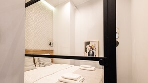 Une chambre d’hôtel avec un lit, un miroir, une lampe fixée au mur et un radiateur.