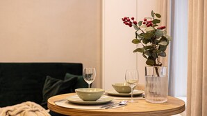 Une table à manger avec deux bols, deux verres à vin et un vase rempli de baies rouges.