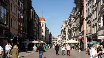 Une rue piétonne bordée de bâtiments historiques, de boutiques et d’espaces aménagés avec des terrasses.