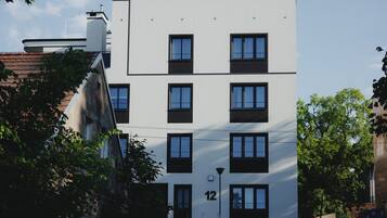 A multi-story building with a white facade, black window frames, and a visible number '12' on the lower right side.