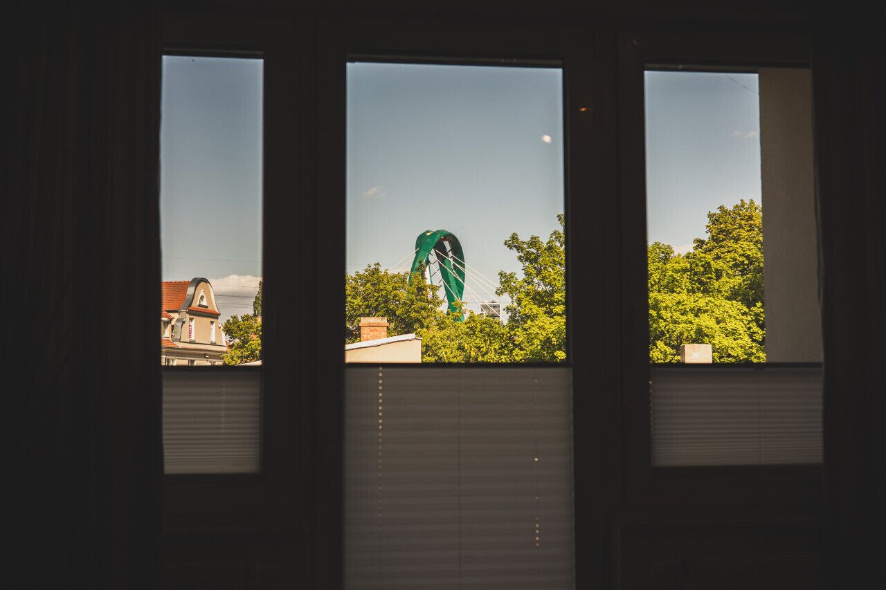 Three windows with a view of a green structure, trees, and buildings.