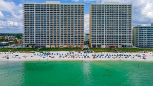 A beachfront hotel with multiple high-rise buildings, a sandy beach with umbrellas, and clear turquoise waters. - Shoreline Serenity by Avantstay Beachfront + Views! (Panama City Beach)