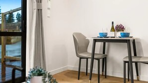 Ein Essbereich mit Tisch, Stühlen, einer Weinflasche und einer Blumenvase.