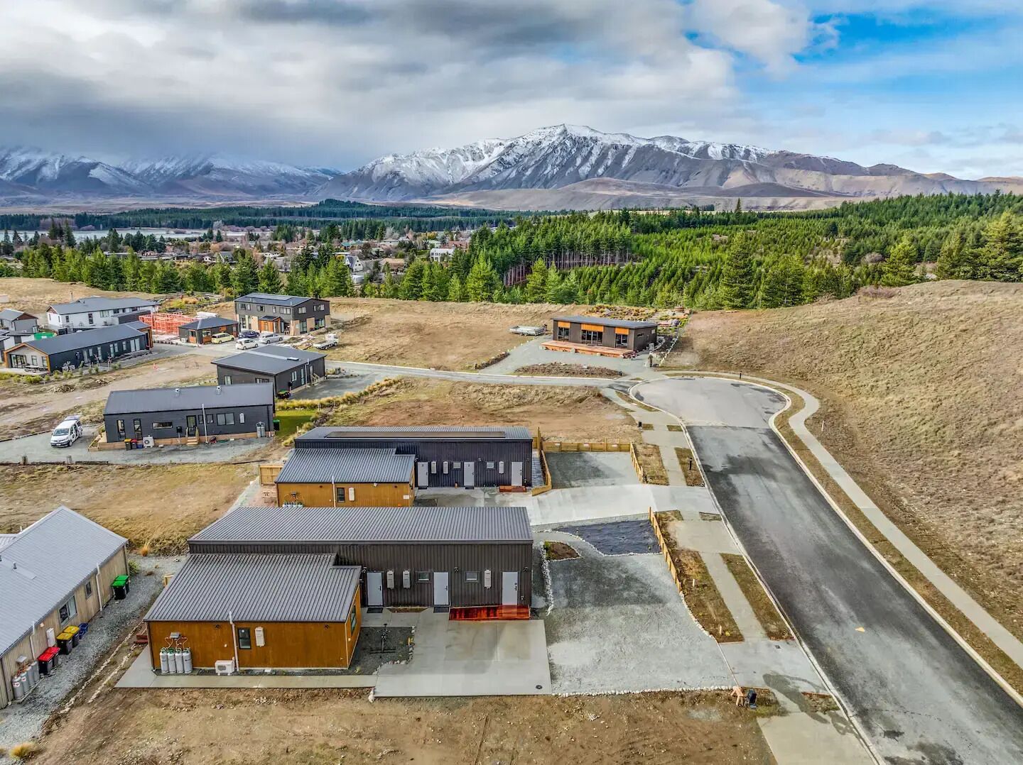 A residential area with modern houses, a winding road, and a mountainous backdrop.