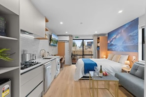 Relax in this stylish room with a large bed, sitting area, and kitchenette, offering a view of the outdoors.