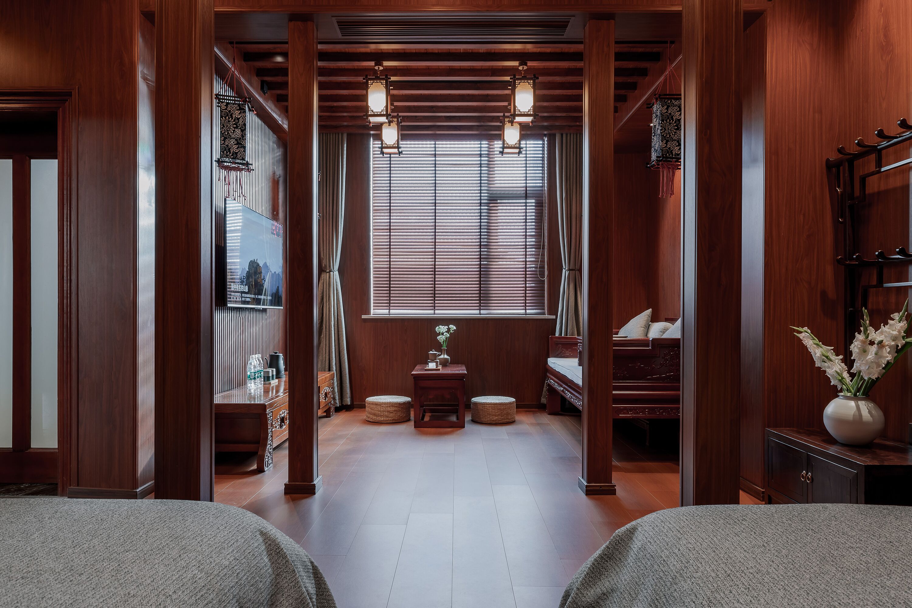 Una tradizionale stanza in stile giapponese con pavimento in tatami, un tavolino con un vaso di fiori e uno shoji che dà accesso a un'altra stanza.