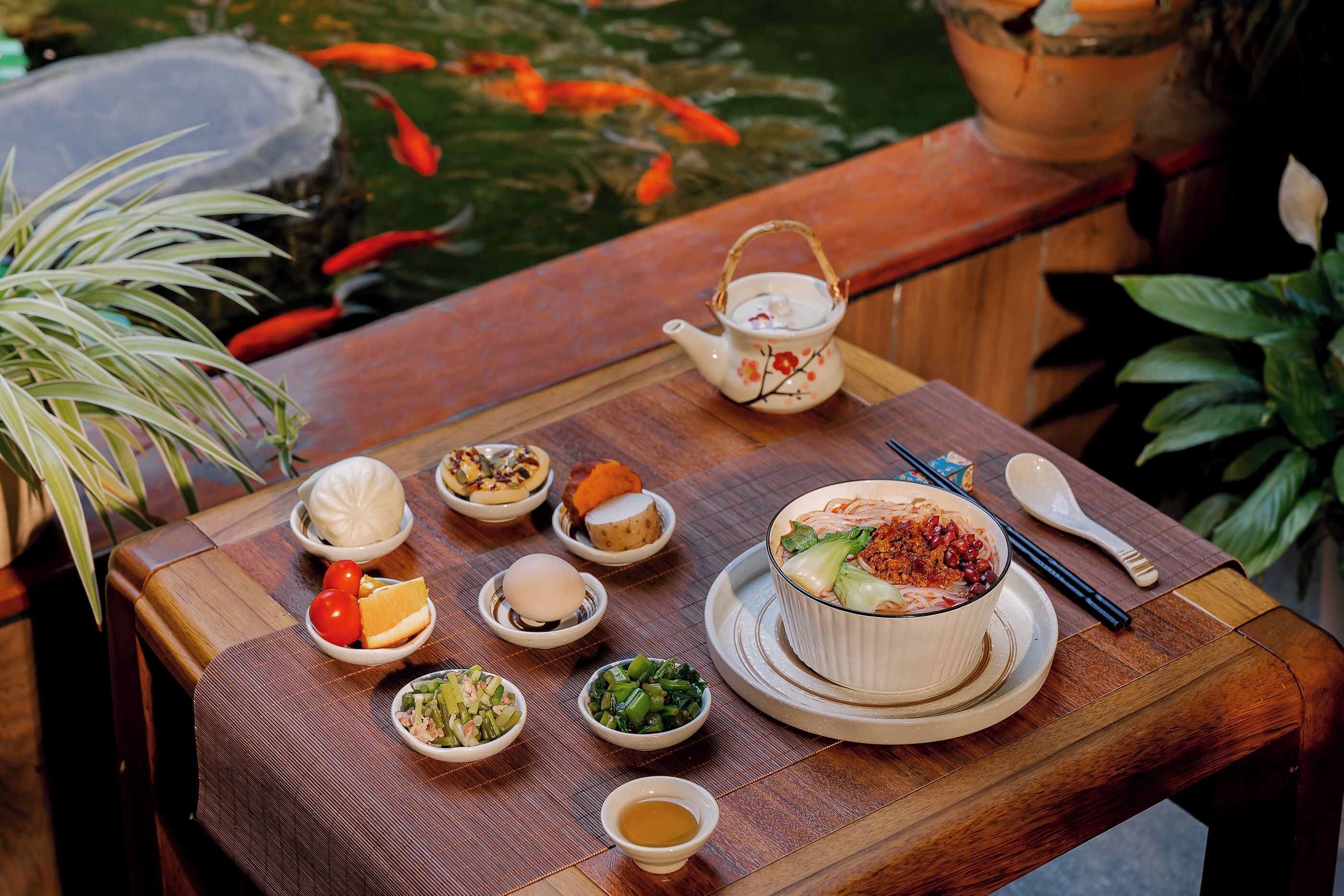 A table with various dishes, a teapot, and chopsticks.