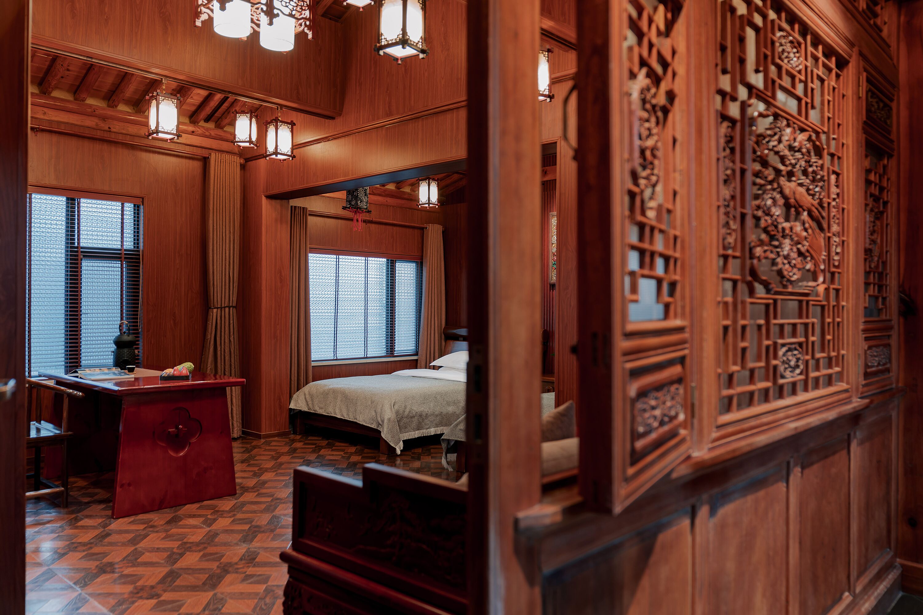 A traditional wooden room with a bed, a desk, and a window with a view.