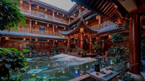 A traditional courtyard with a central pond, wooden architecture, and potted plants. - Spirited Silky Inn (Dali)