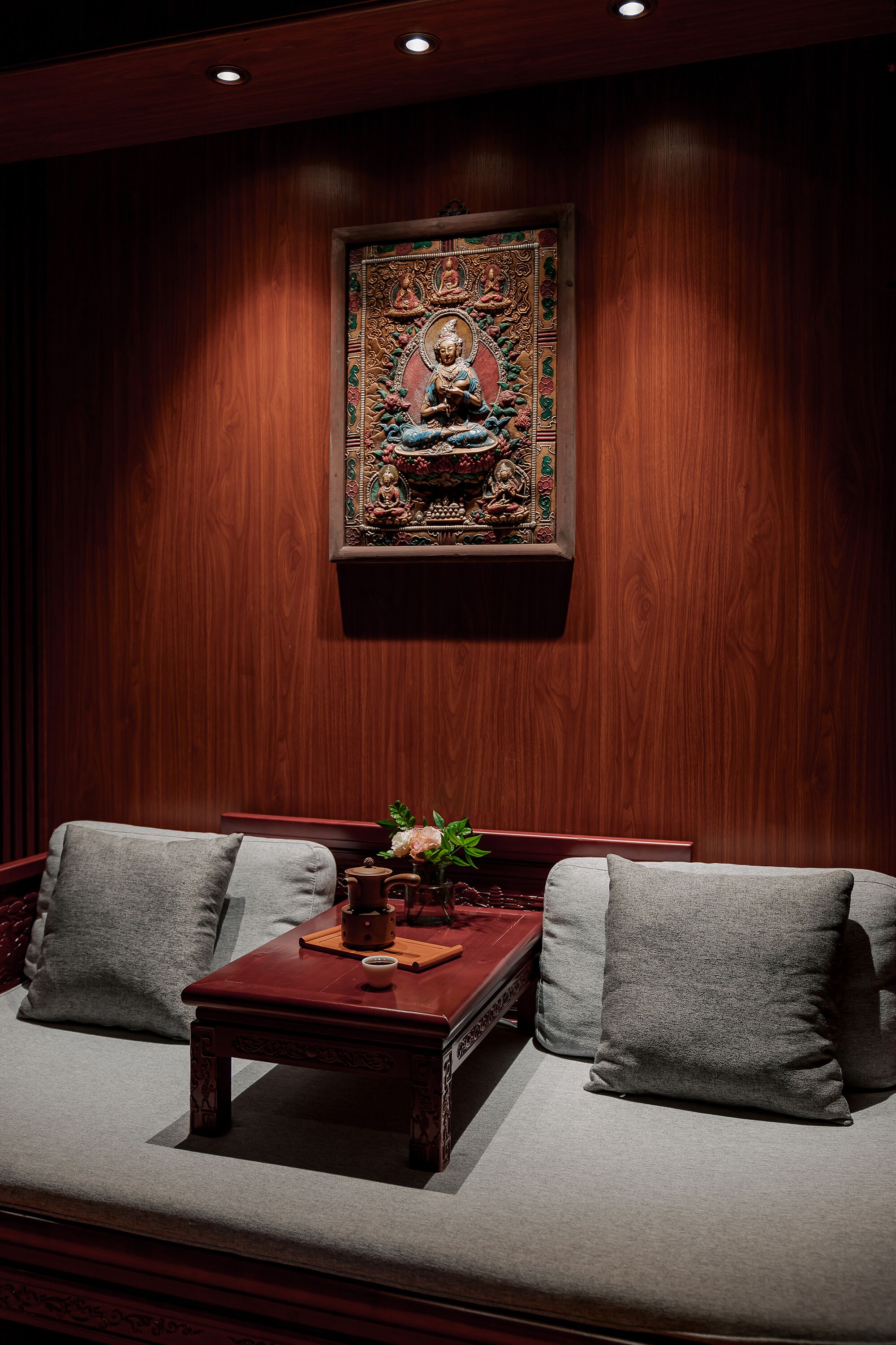 A wooden wall with a framed artwork and a sofa with cushions.