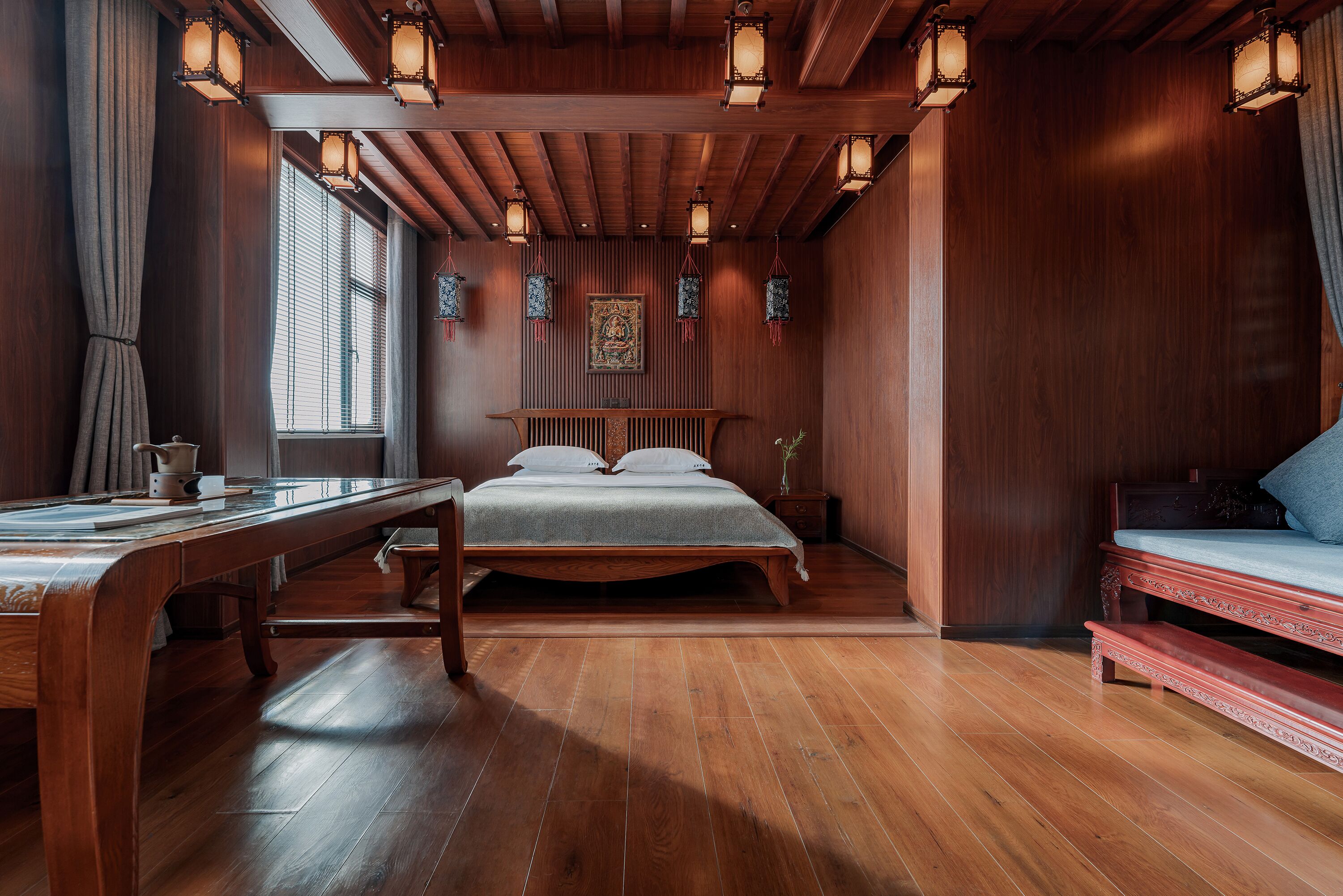 Un dormitorio de madera con una cama, un escritorio y un ventanal.