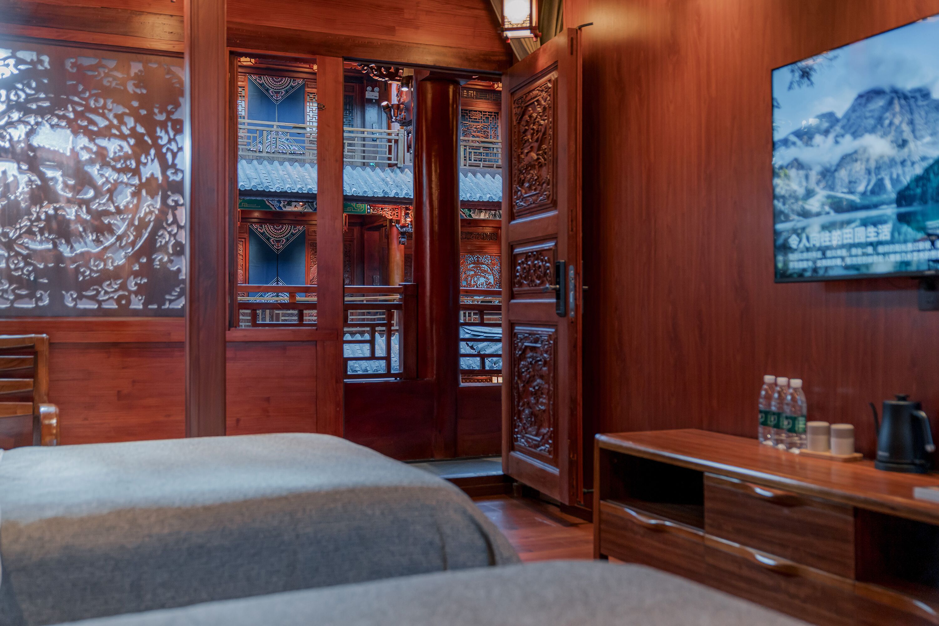Une chambre traditionnelle en bois, avec un lit, un bureau et un téléviseur fixé au mur.