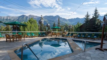 A pool area with lounge chairs and a view of mountains.