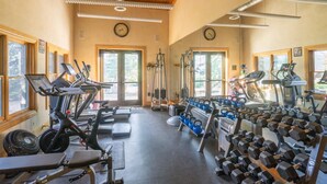 Une salle de sport équipée de tapis de course, de bancs de musculation et de kettlebells.