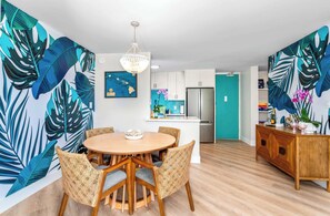A modern kitchen with white cabinets, a stainless steel refrigerator, and a teal accent wall.