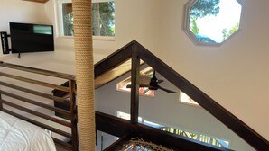 A bedroom with a wooden bed, a rope cat tree, a ceiling fan, and a skylight. - The Treehouse at Hulili Farm - NEW  (Hakalau)