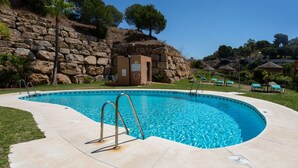 A swimming pool with a stone wall and trees in the background. - Los Lagos de Santa Maria by Interhome (Elviria, Marbella)