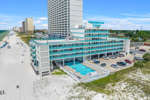 Un hotel con piscina, vistas a la playa y aparcamiento.