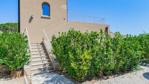 Ein Gebäude mit einer beigen Fassade, einem kleinen Rundbogenfenster und einer Treppe, die zu einem Balkon führt.