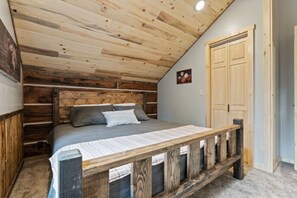 Ein Schlafzimmer mit Holzboden, einem Bett mit Holz-Kopfteil und einer Tür.