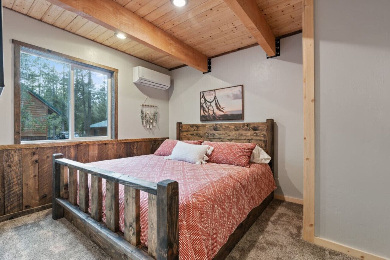 Ein Schlafzimmer mit einem hölzernen Bett, einem großen Fenster, einer Klimaanlage und einem Bild an der Wand.